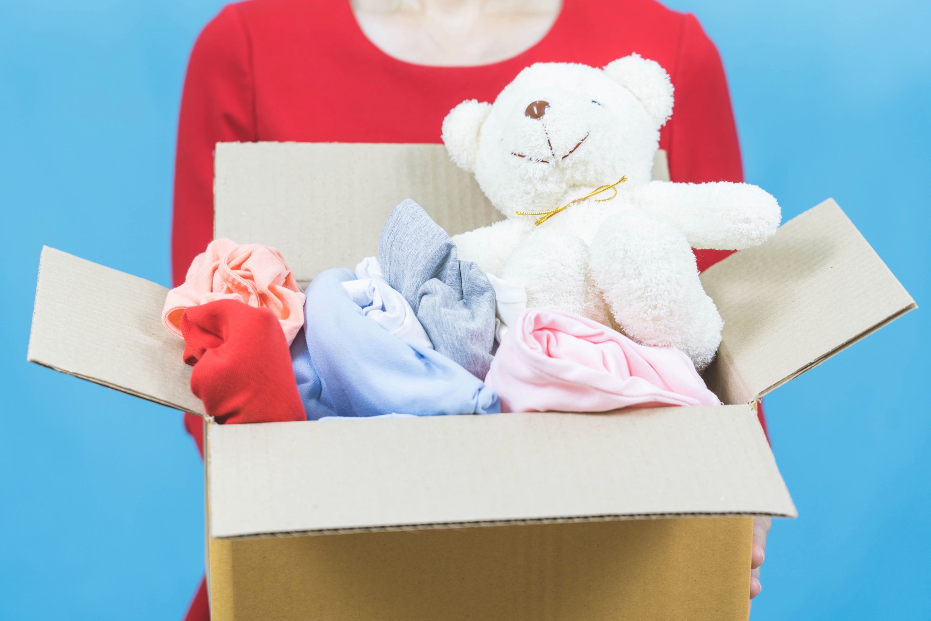 Donation Concept. Woman holding a Donate Box with full of Clothes and doll,selective focus